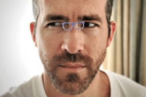 image shows actor Ryan reynolds looing sideways wearing tiny glasses