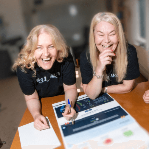 Images shows, from left to right, Jo Leigh and nichola howard from launch nw laughing towards the camera whilst working on a table