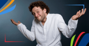 A person with curly hair wearing a white shirt and khaki pants, shrugging with open palms.