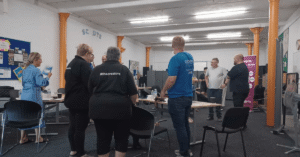 A room full of people attending a networking event, standing in small groups and talking with one another